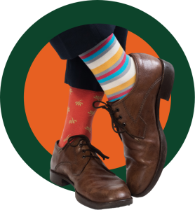 A man's brown leather shoes, crossed, wearing two wildly different unmatched socks\.