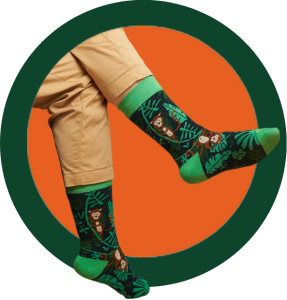 A pair of legs, sitting down and crossed, wearing green socks that feature monkeys\.